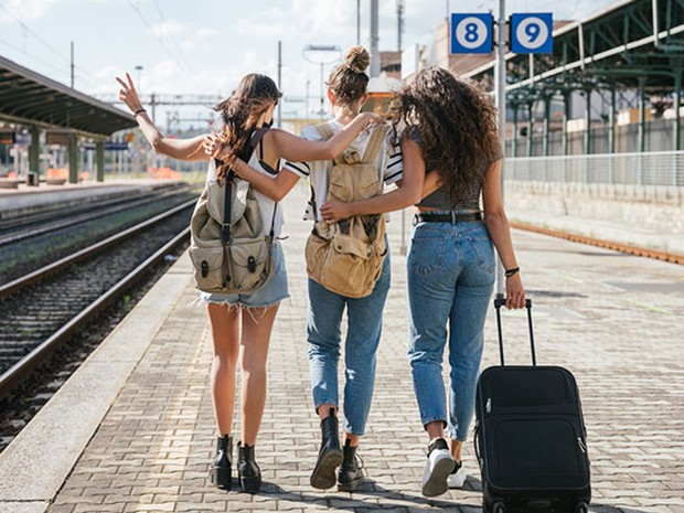 Drie vriendinnen met bagage op een station