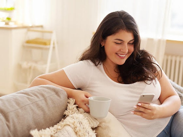 Vrouw zit op de bank met telefoon