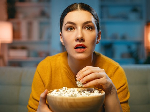 Vrouw kijkt tv en eet popcorn huiskamer