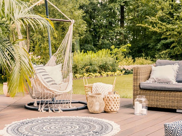 tuin met macrame hangstoel en tuinbank en gevlochten manden en tuinkleed