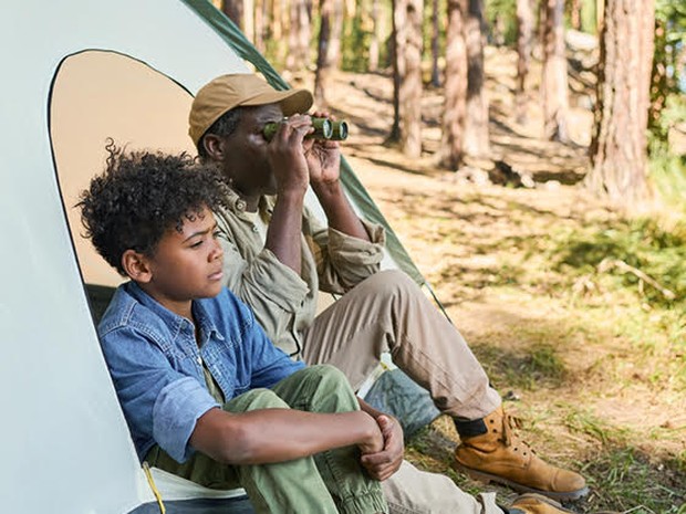 Man met verrekijker en jongen in tent