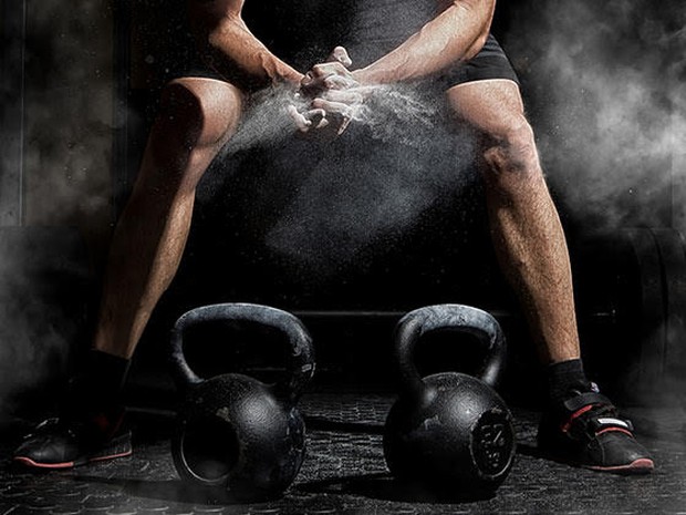 man in sportschool met gewichten en magnesium