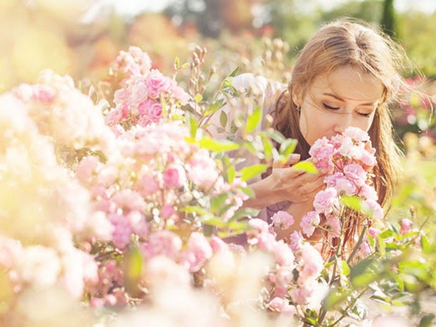 Een vrouw die buiten aan bloemen ruikt