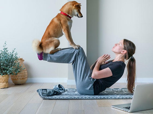 Een vrouw die yoga beoefent met haar hond