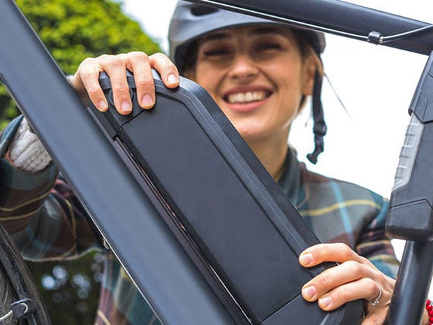 Een vrouw die de accu van haar elektrische fiets vasthoudt
