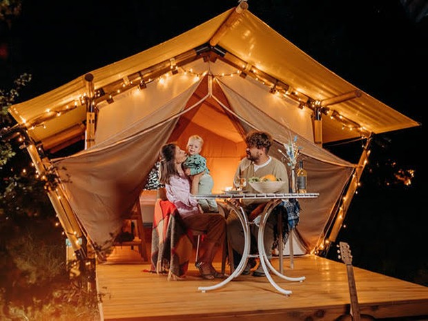 Een gezin die de avond doorbrengt voor de tent van een glamping