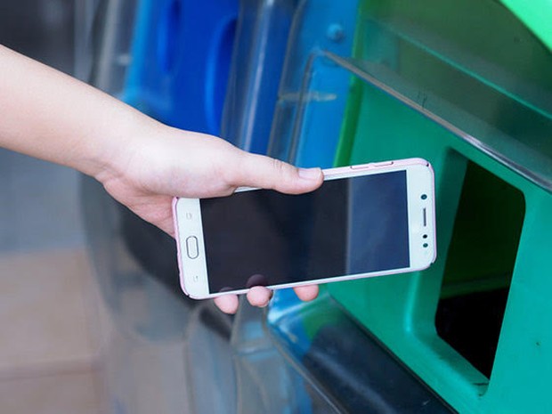 Iemand die een oud mobieltje inlevert in een speciale bak