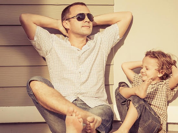 Een vader en zoon die tegen een muur aan relaxen in de zon