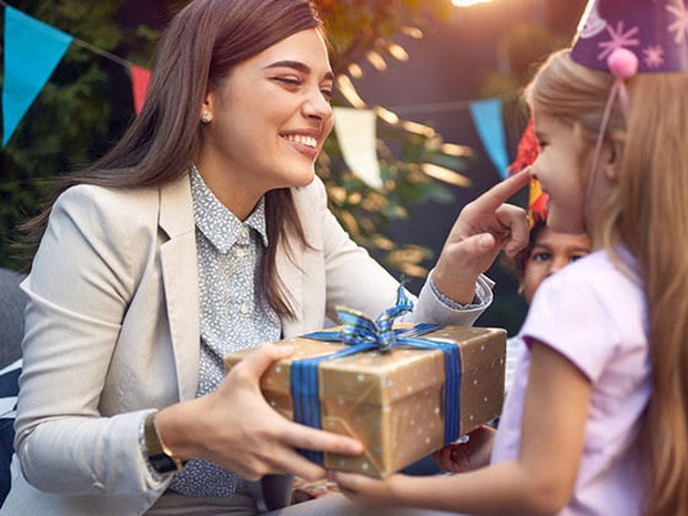 Een jarig meisje met feesthoed op krijgt een cadeau van een vrouw