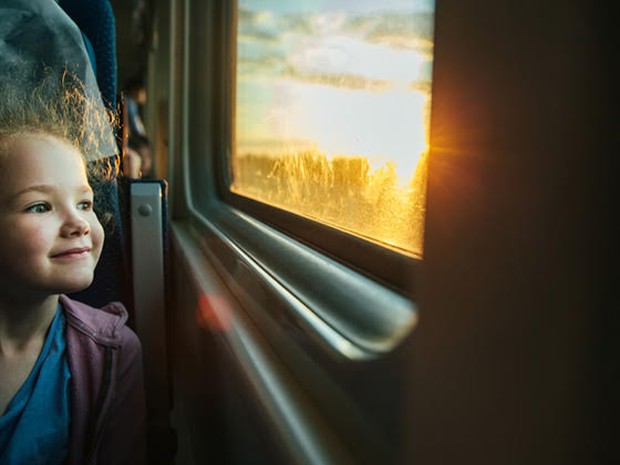Een lachend meisje dat vanuit de trein naar buiten kijkt