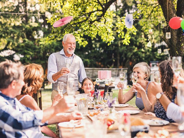 Een feestje met familie in de tuin die aan een tafel proosten