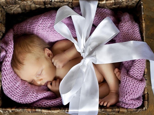 Een slapende baby in een giftbox met strik erom