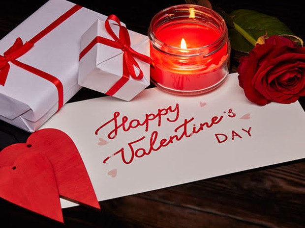Cadeautjes, een kaars en roos op een envelop met daarop Happy Valentine's day
