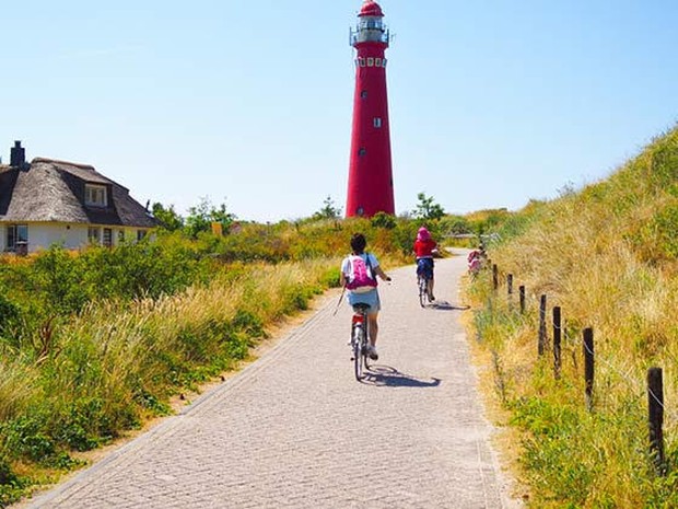 Twee fietsers die langs een vuurtoren fietsen