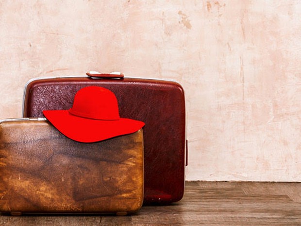 Twee vintage koffers met bovenop een rode hoed op de grond