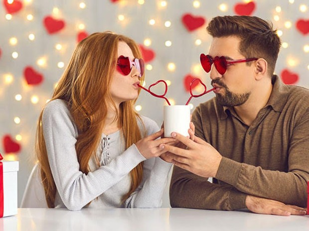 Een man en vrouw drinkend uit 1 glas tijdens een date