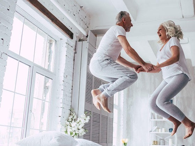 Een senioren stel springend op een bed