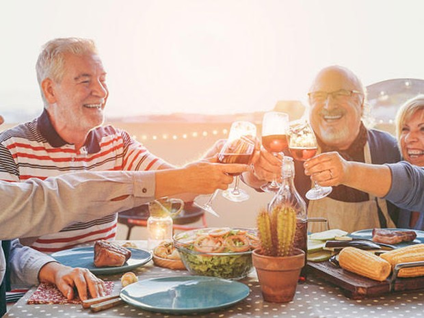 Twee seniorenstellen die proosten tijdens het eten