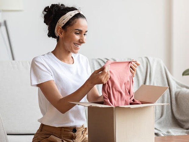 Vrouw pakt kleding uit kartonnen doos